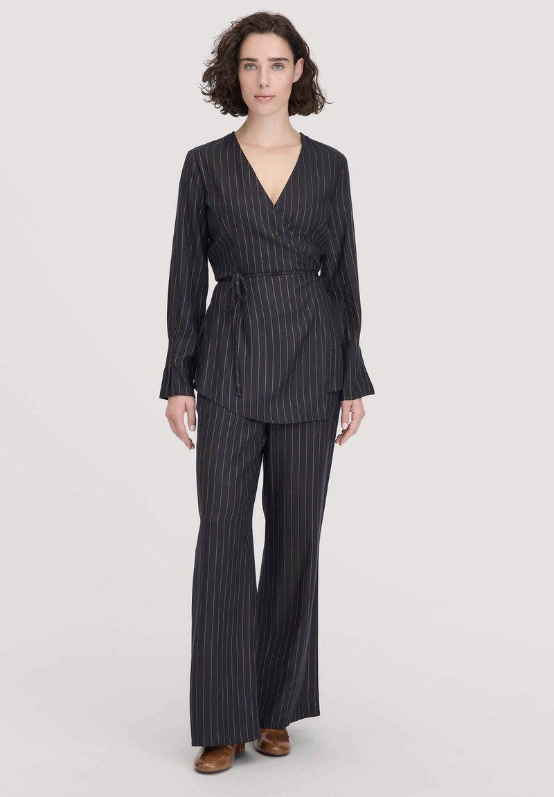 Top avvolgente nero a righe con maniche lunghe abbinato a pantaloni larghi coordinati. Strisce verticali multicolori e dettaglio della cintura in vita.