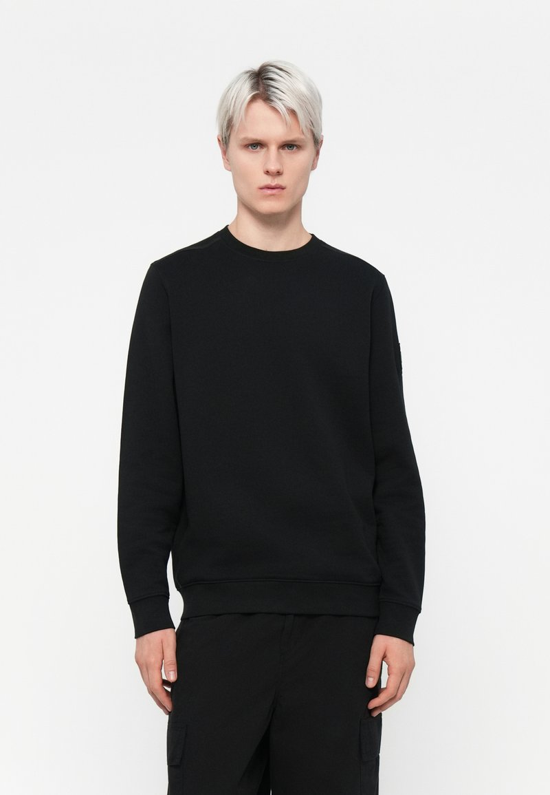 Sort sweatshirt med rund halsudskæring, lange ærmer og ribbede manchetter, lavet af et glat, struktureret stof, med en subtil detalje ved skuldersømmen.