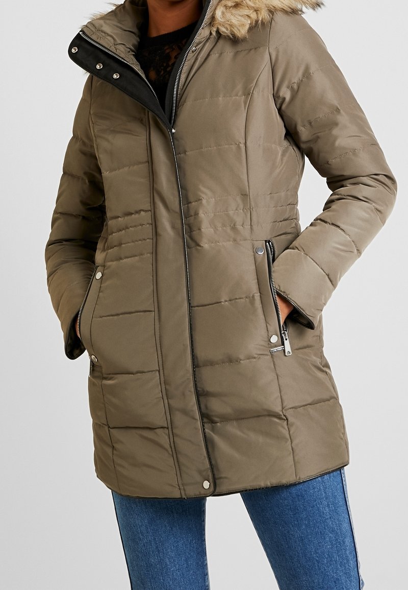 Olijfgroene pufferjack met een bontgevoerde capuchon, ritszakken en horizontale stiksels. Gladde stof met een matte afwerking.