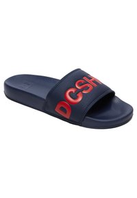 Sandaalit sinivalkoisella värillä, valmistettu synteettisestä materiaalista, jossa on teksturoitu hihna. Ominaisuuksiin kuuluu rohkea punainen "DCSH" -logo nauhassa.