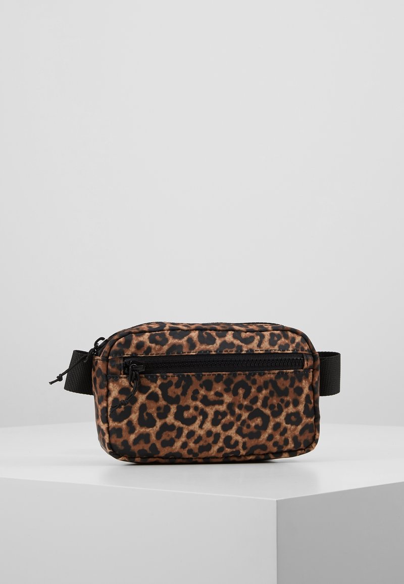 Sac banane rectangulaire imprimé léopard avec poche zippée noire et sangle noire réglable sur un socle blanc.