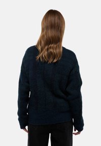 Pull en tricot surdimensionné bleu marine avec une finition texturée, un ourlet côtelé et des manches longues, offrant une coupe décontractée et un tissu doux.