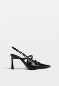 Escarpins slingback en cuir noir avec un bout pointu, dotés de brides croisées et d'études décoratives, montés sur un talon stiletto fin.