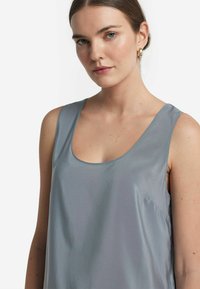 Ljusgrå satinlinne med vid rundad halsringning och rena linjer. Slät textur med minimal detaljering.