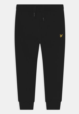 Sorte joggingbukser med elastisk talje, snøre, manchetter ved anklerne og lille gul ørnelogo på øverste venstre lår.