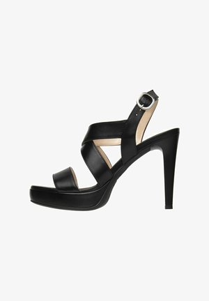 Sandale à talons hauts en cuir noir avec plateforme, présentant des brides croisées, une ouverture sur l'orteil et une boucle de cheville réglable. Texture lisse.