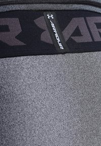 Tessuto atletico grigio con una texture liscia, dotato di una cintura elastica nera con il marchio "Armour" in grigio scuro.