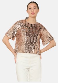 Rose gold sequin top with a round neckline and short sleeves, featuring a loose fit and a shiny, textured surface.