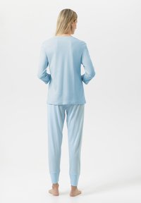 Jasnoniebieski top z długim rękawem oraz pasujące, paskowane spodnie do piżamy ze ściągaczami u dołu nogawek, wykonane z miękkiego materiału, cechujące się luźnym krojem i gładką teksturą.