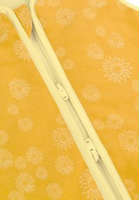 Gelber Reißverschlussanzug mit einem ganzflächigen weißen Sonnenblumenmuster. Das Material wirkt weich, mit einem passenden Reißverschluss und cremefarbenen Akzenten.