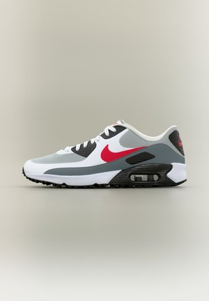 Baskets Nike Air Max blanches, grises et noires avec un logo Swoosh rouge et une semelle avec coussin d'air visible, profil latéral sur un fond neutre.