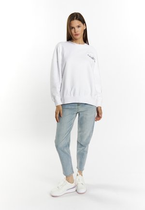 Witte sweatshirt met een ronde hals en geborduurde details, gecombineerd met lichtblauwe jeans en witte sneakers. Zachte stof, relaxte pasvorm.