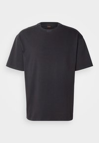 T-shirt noir à manches courtes col rond avec un logo discret de la marque sur la poitrine et à l'intérieur du col sur un fond uni.