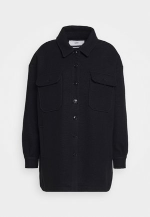 Czarna oversize kurtka z kołnierzem, długimi rękawami i dwoma dużymi kieszeniami z patkami na piersiach.