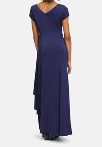 Mörkblå, golvlång klänning med korta ärmar, V-rygg och sidoklyfta. Slät tyg med en dold dragkedja på baksidan.