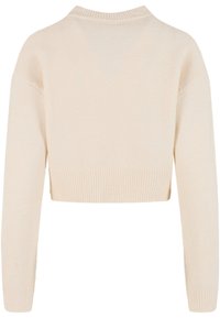 Krátký svetr z měkké béžové pleteniny. Má žebrovaný lem a manžety, kulatý výstřih a volný střih s spadlými rameny.