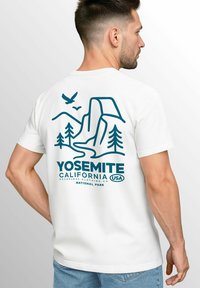 Weißes T-Shirt mit kurzen Ärmeln, das eine blaue Grafik von Yosemite, Kalifornien, zeigt, mit Bäumen, Bergen und Vögeln, beschriftet mit "Yosemite National Park."