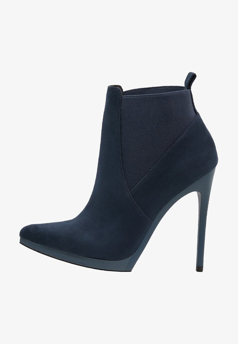 Bottine à talon haut bleu marine en daim avec un bout pointu, un panneau latéral élastique et un talon aiguille élancé. Texture lisse.