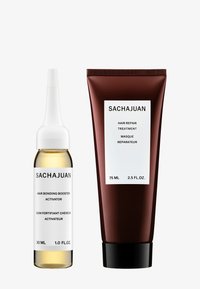 SACHAJUAN hårforsterker i en klar glassflaske med hvit hette, og en burgunder hårreparasjonskremtube med svart lokk.