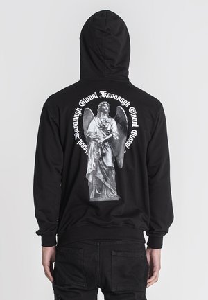 Sort hættetrøje med et stort sort-hvidt print af en engelstatue på ryggen, omgivet af tekst i hvid. Blødt stof.