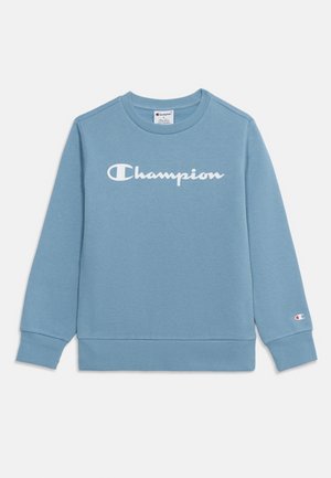 Svetlomodrá dlhá mikina Champion s bielym logom na hrudi a malým logom na manžete ľavého zápästia.