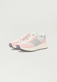 Sportssko med en blandet materialedesign, som har en rosa og grå fargepalett, hvite detaljer og teksturerte semsket skinn-detaljer.