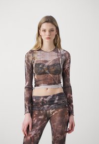 Langermige, doorschijnende top en bijpassende leggings in gestructureerde, meertonenstof met een vervaagd abstract patroon in bruine en grijze tinten.