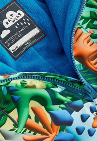 Blue fleece lining with a colorful patterned inner layer featuring plants and shapes. Zipper detail and fabric tag labeled "Rain Wear."