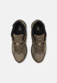 Brązowe buty sportowe z cholewką z siateczki i zamszu, wiązane na sznurówki, z wyściełanym językiem i czarnym wnętrzem. Na boku znajduje się logo.