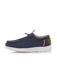 Scarpa in tela blu navy con suola in gomma bianca, chiusura con lacci e accento marrone a contrasto sul tallone. Texture liscia e design leggero.