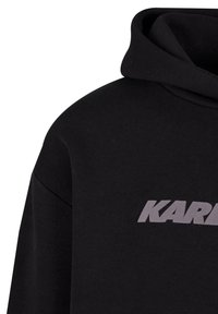 Černá mikina s měkkou texturou a velkým šedým logem "KARL" umístěným na přední části. Disponuje klasickou kapucí a volným střihem.