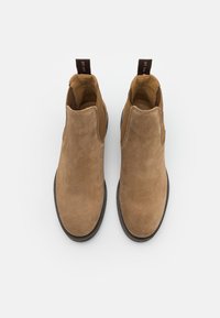 Brown suede ankle boots with elastic side panels, round toe, and pull tabs. Smooth texture and a rubber sole for traction.