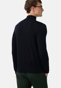 Marineblauer Strickpullover mit hohem Kragen, taillierten Ärmeln und glatter Textur. Weicher Stoff mit einem klaren, minimalistischem Design.