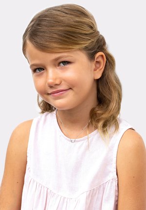 Meisje met lichtbruin haar in zachte golven gestyled, gekleed in een mouwloze roze linnen jurk en een zilveren ketting met een vlinder bedel.