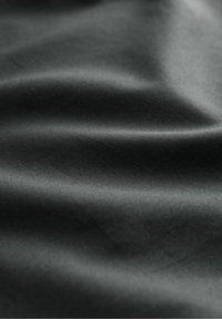 Tissu noir avec une finition lisse et brillante ; présente un drapé doux et des variations subtiles de texture. Aucun motif ni élément métallique visible.