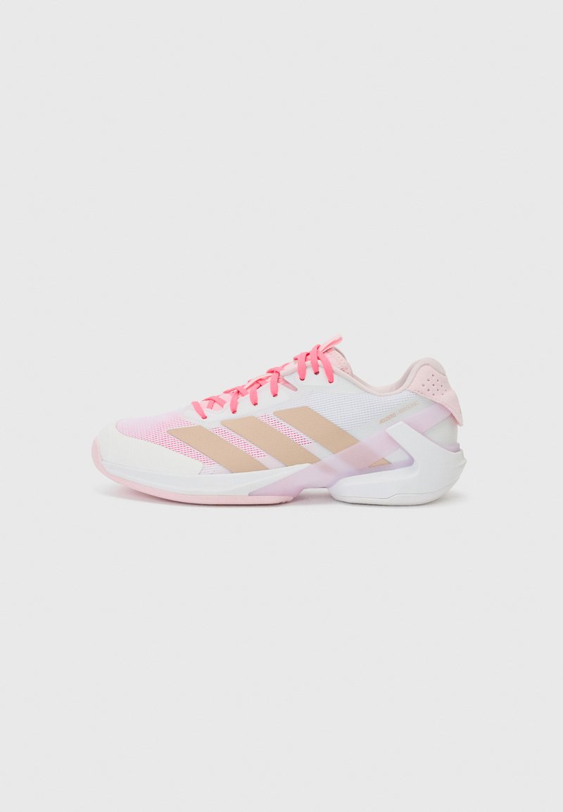 Pink and white athletic shoe with mesh upper, beige stripes, and textured elements. Features a rounded toe and contrasting rubber sole.