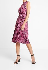 Kleid mit pinkem Leopardenmuster, ärmellos, mit gerafftem Taillenbereich und fließendem Rock. Aus glattem Stoff und mit einem Gürtel-Akzent.