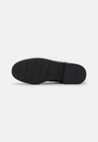 Black rubber outsole with textured pattern featuring the "Calvin Klein" logo. Flat, smooth surface with a slight curvature at the edges.