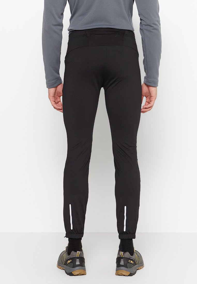 Pantaloni atletici neri realizzati in materiale leggero, con accenti riflettenti nei polsini. Il design è affusolato e aderente.