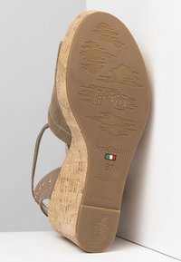 Beige Wildledersandale mit Keilabsatz aus Kork, mit dekorativen Nieten, strukturiertem Gummisohle und eingravierten Markendetails auf der Unterseite.