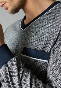 Suéter de patrón marino con un diseño geométrico, puños acanalados y un bolsillo en contraste con detalles de costura. Textura suave, corte relajado.