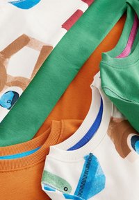 Stapel bunter Kinderkleidung, darunter grüne, orangefarbene und bedruckte Oberteile mit blauen und braunen Mustern, die Ausschnitte und Ärmel zeigen.