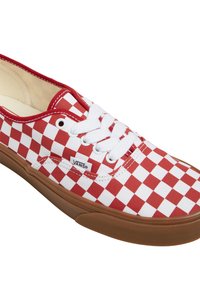 Baskets Vans à carreaux rouges et blancs avec des lacets blancs et une semelle en caoutchouc marron, étiquette de logo sur le côté visible, montrées sur un fond blanc.