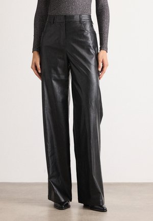Black leather wide-leg trousers with a smooth texture, high waist, and subtle front pockets, paired with a fitted, ribbed top.