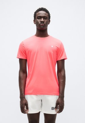 Kortærmet sportst-shirt i en lys koralfarve, lavet af fugttransporterende stof. Har en lille logo på venstre bryst.