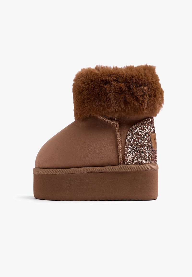Botas de tobillo de ante sintético marrón con un cuello de piel sintética marrón esponjoso, un acento de brillo texturizado en la parte trasera y una suela de goma plana.