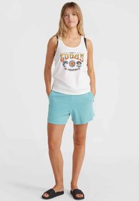 Weißes Tanktop mit mehrfarbigem "Heute ist perfekt"-Grafik, kombiniert mit hellblauen Shorts und schwarzen Riemchensandalen.