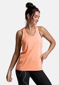 Pfirsichfarbene Sporttanktop mit Rundhalsausschnitt und Mesh-Textur, kombiniert mit schwarzen Leggings, die über anguläre, reflektierende Muster verfügen.