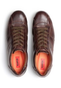 Braune Ledersneaker mit rundem Zehenbereich, olivgrünen Schnürsenkeln und kontrastierenden orangen Innensohlen. Mit dezentem Logo und abgesteppten Details.