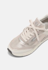 Baskets beiges avec des détails en mesh et en cuir lisse, bout rond, lacets plats, accents argentés et semelle blanche rembourrée.